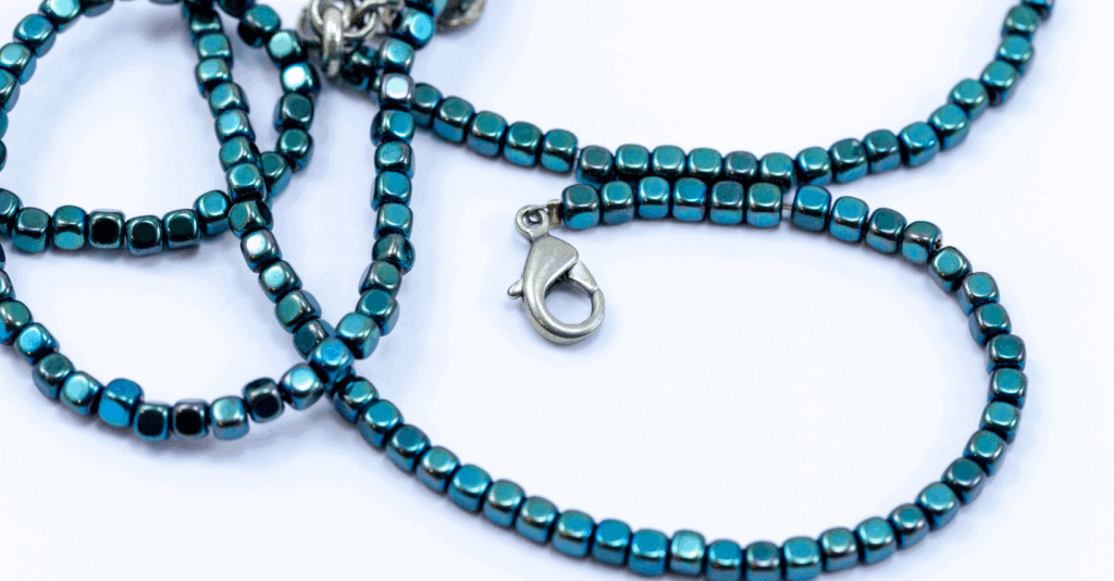 A lobster clasp at the end of a string of blue hematite cube beads